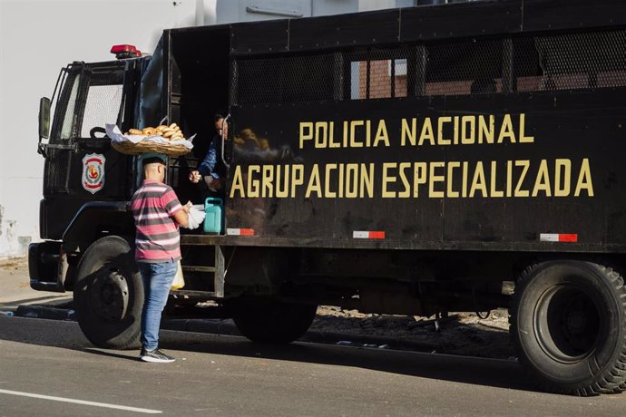 Archivo - May 11, 2023, Asuncion, Paraguay: A person carring a basket of 'chipa', Paraguay's popular snack food, on his head makes a sell to a police officer during a demonstration against the alleged electoral fraud in the recent general elections held o