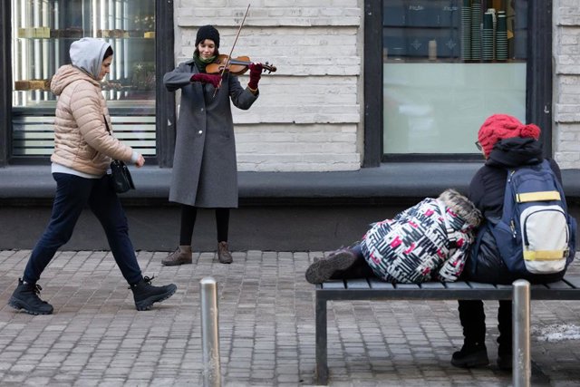 Una persona toca el violín ante peatones en el centro de Kiev