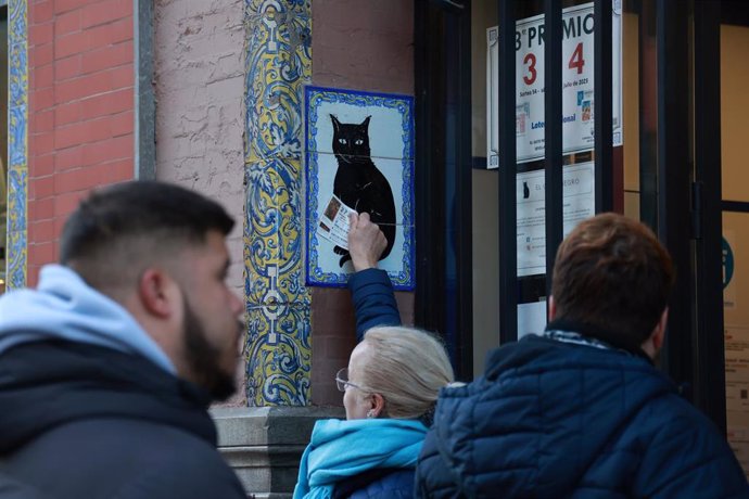 Una persona frota el décimo de Lotería de Navidad que acaba de adquirir en la Administración del Gato Negro en la Avenida de la Constitución de Sevilla. A 19 de diciembre de 2023, en Sevilla (Andalucía, España).