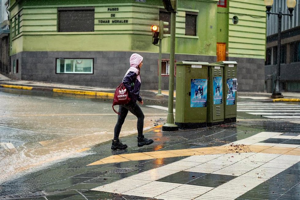 Archivo - Una chica, con capucha, camina por una calle anegada por la lluvia, a 25 de septiembre de 2022, en Las Palmas de Gran Canaria, Canarias (España)
