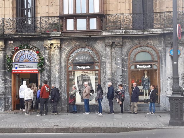 Varias personas esperan paa comprar lotería ante una administración en Bilbao.