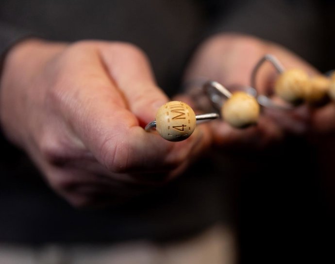 Una persona sujeta uno de los premios de las bolas de los bombos del Sorteo Extraordinario de Navidad, en el Teatro Real, a 15 de diciembre de 2023, en Madrid (España). El próximo 22 de diciembre se celebra el Sorteo Extraordinario de Navidad 2023, con 