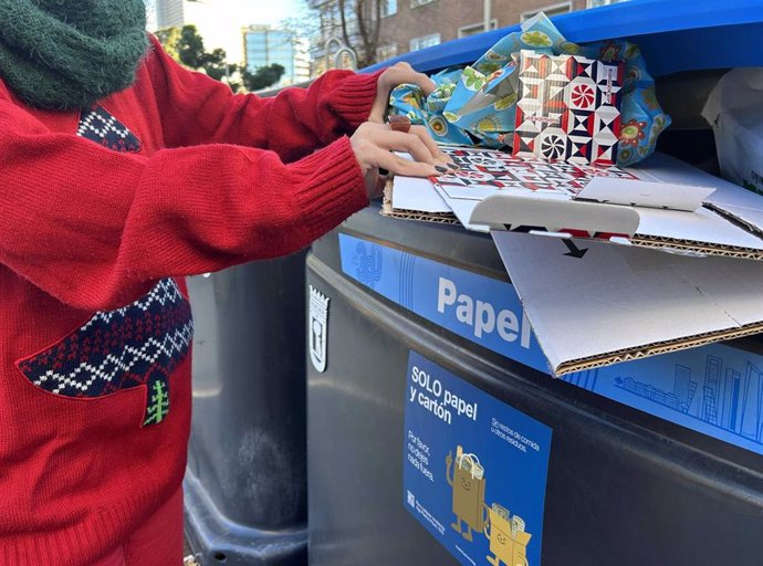 Persona reciclando el papel y cartón de los regalos de Navidad.