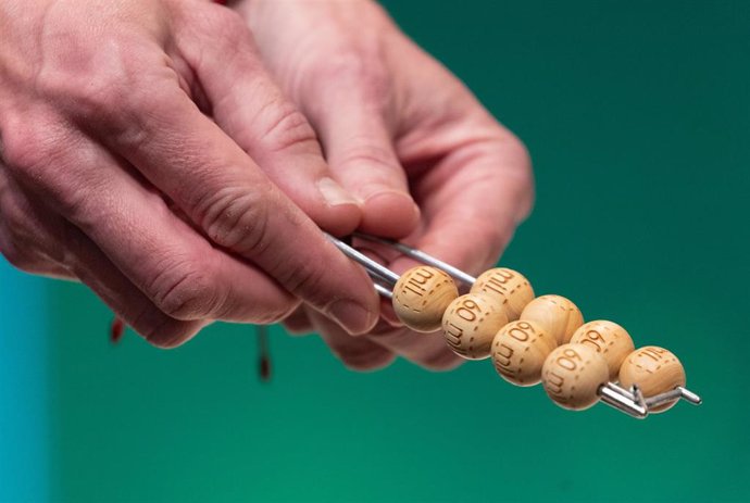 Un hombre enseña las bolas con la cantidad de dinero de uno de los premios al inicio del Sorteo Extraordinario de la Lotería de Navidad 2023 