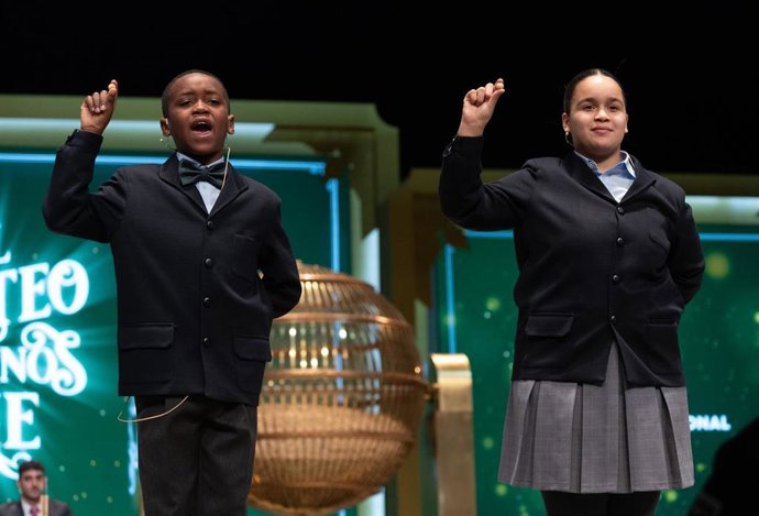Paula Figuereo Figuereo y Ángel Albaga Elebiyo cantan un quinto premio, el número 01568, durante el Sorteo Extraordinario de la Lotería de Navidad 2023 en el Teatro Real de Madrid, a 22 de diciembre de 2023, en Madrid (España). El sorteo se celebra en e
