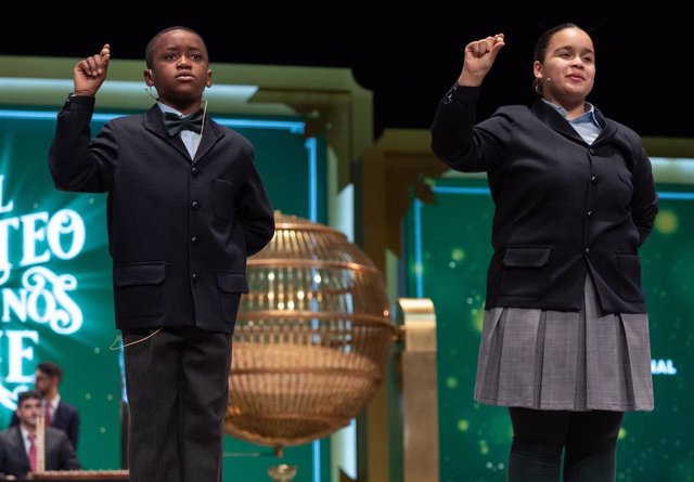 Paula Figuereo Figuereo y Ángel Albaga Elebiyo cantan un quinto premio, el número 86.007, durante el Sorteo Extraordinario de la Lotería de Navidad 2023 en el Teatro Real de Madrid, a 22 de diciembre de 2023, en Madrid (España). 