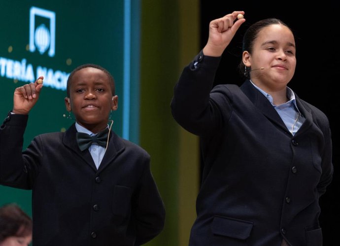 Paula Figuereo Figuereo y Ángel Albaga Elebiyo cantan un quinto premio, el número 86.007, durante el Sorteo Extraordinario de la Lotería de Navidad 2023 en el Teatro Real de Madrid, a 22 de diciembre de 2023, en Madrid (España).