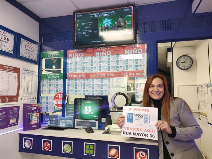 Responsable de la administración de la calle Rúa Antigua, 36, de Salamanca con un cartel del número premiado con un quinto premio