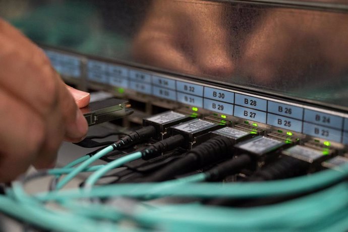 Archivo - FILED - 05 October 2021, Baden-Wuerttemberg, Stuttgart: An employee of the High Performance Computing Centre HLRS connects a fibre optic cable. Photo: Marijan Murat/dpa