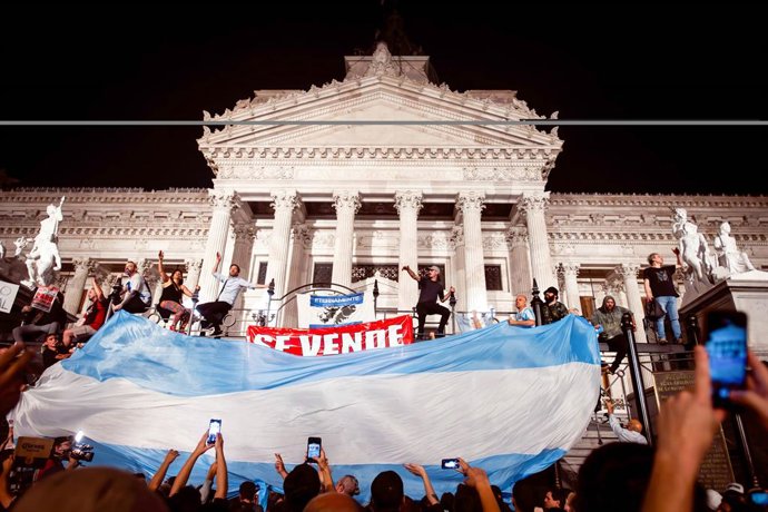 21 December 2023, Argentina, Buenos Aires: Protesters hold an Argentine flag in front of the National Congress during an anti-government demonstration. Photo: Mariana Nedelcu/SOPA Images via ZUMA Press Wire/dpa