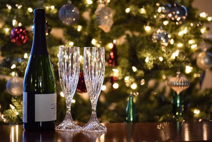 Archivo - Copas y botella delante un árbol de navidad.