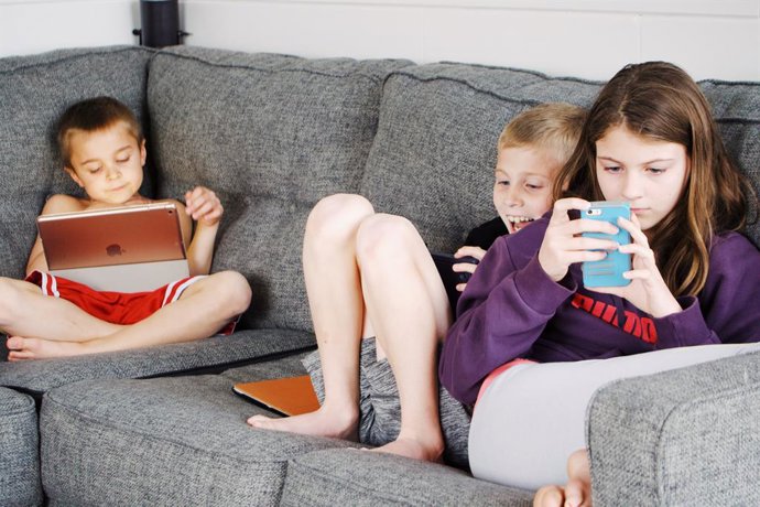 Archivo - Niños utilizando dispositivos móviles.