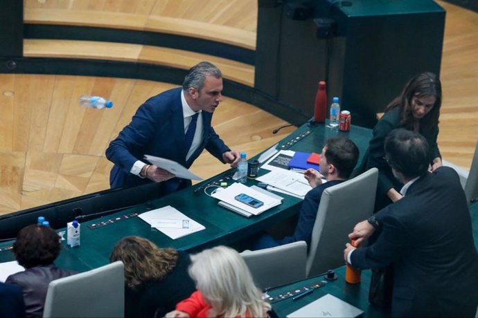 Momento en el que el portavoz de Vox en el Ayuntamiento de Madrid, Javier Ortega Smith, se encara y tira unos papeles y una botella de agua al edil Eduardo Fernández Rubiño, concejal de Más Madrid, en su escaño.