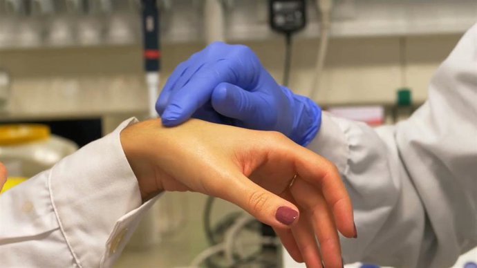 Archivo - Un médico echando crema en la mano de un paciente.