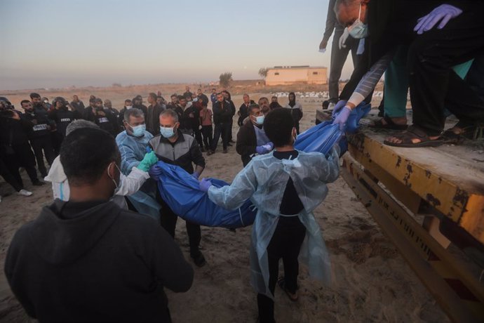 26 December 2023, Palestinian Territories, Rafah: Medics unload the bodies of 80 Palestinian victims, killed in the north of the Gaza Strip, at a mass grave in the city of Rafah. Israeli army delivered the bodies this evening through the Kerem Shalom cr