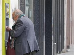 Archivo - Persona mayor sacada dinero de un cajero. Archivo