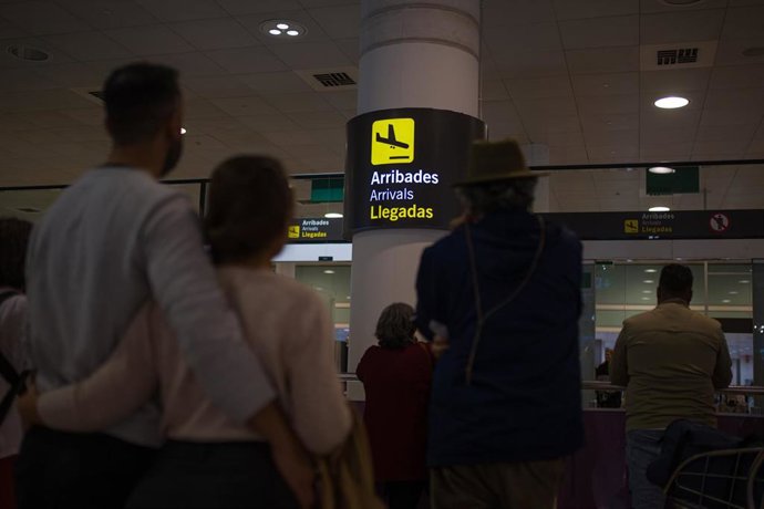 Archivo - Un grupo de personas esperan en el aeropuerto de Barcelona.