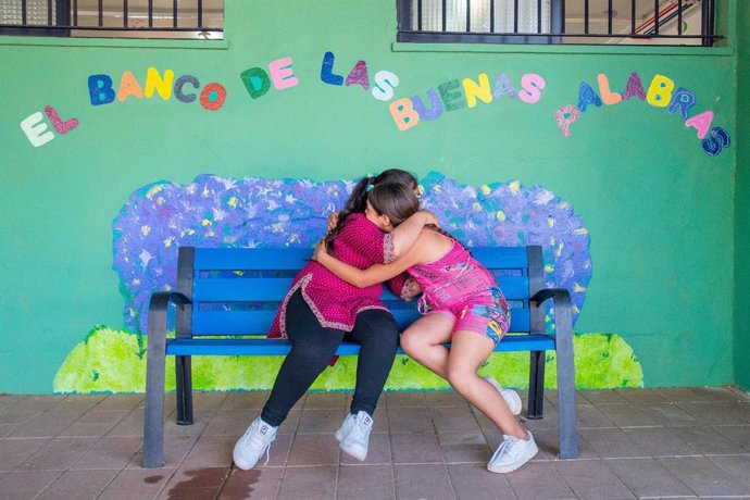 Dos niñas se abrazan en un centro educativo.
