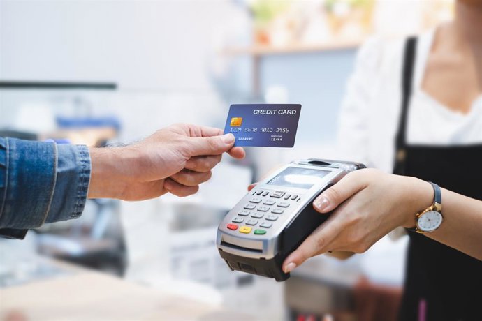 Archivo - Una persona pagando con tarjeta de crédito en un datafono de un comercio.