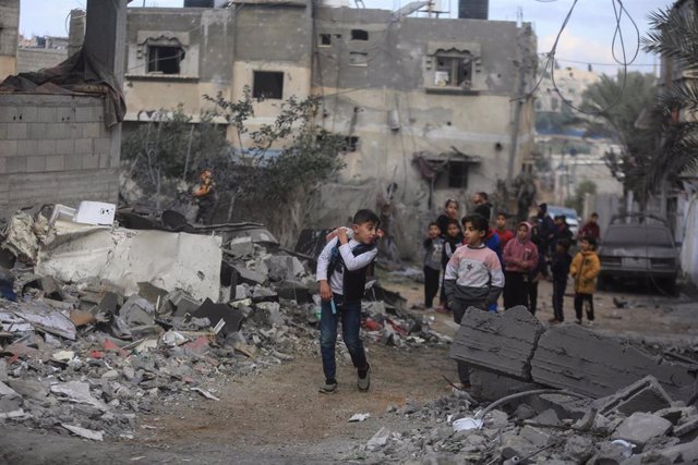 Niños palestinos en Gaza junto a los escombros de un edificio bombardeado