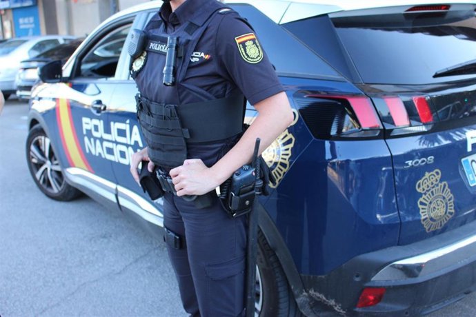 Archivo - Un agente de Policía Nacional junto a un vehículo del cuerpo.