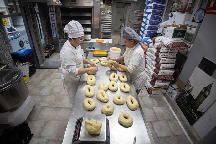 Dos personas trabajan la masa durante la elaboración de roscones de Reyes, en el Obrador El Panazo, a 4 de enero de 2023