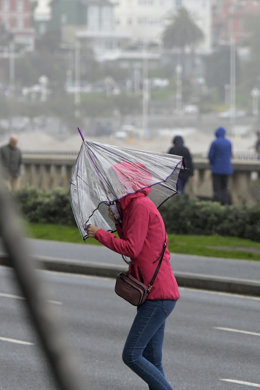 Archivo - Una persona se protege de la lluvia y el viento con un paraguas en A Coruña, Galicia (España). 