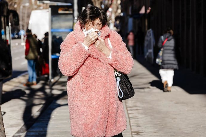 Una persona se limpia la nariz por una calle de Madrid.