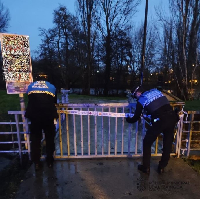 Agentes de la Policía Municipal de Pamplona cortan el acceso a las pasarelas del río Arga.