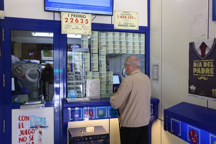 Archivo - Un hombre compra lotería en una Administración de Lotería.