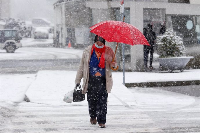 Un hombre se refugia de la nieve con un paraguas en una calle de Pedrafita do Cebreiro, a 5 de enero de 2024, en Pedrafita do Cebreiro, Lugo, Galicia (España). Un temporal de nieve ha entrado por el norte de Galicia en altitudes superiores a 800 metros. E