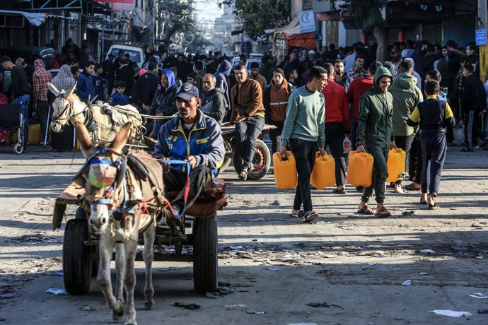 08 January 2024, Palestinian Territories, Rafah: Displaced Palestinians arrive with bottles and jerrycans to fill them with water. Charitable organizations are distributing water to people affected by the war in Gaza. Photo: Abed Rahim Khatib/dpa