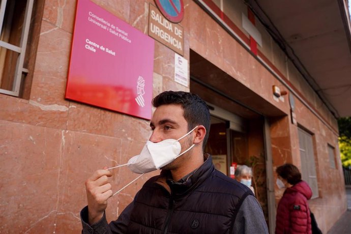 Una persona se quita la mascarilla al salir de un centro de salud.