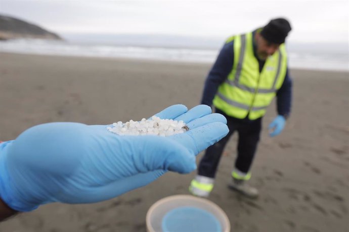 Archivo - Un operario de TRAGSA coge con la mano pellets de plástico, en la playa Otur, a 9 de enero de 2024, en Valdés, Asturias (España). 