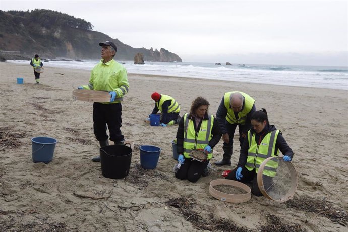 Operarios de TRAGSA recogen pellets de plástico, en la playa de Aguilar, a 9 de enero de 2024, en Muros de Nalón, Asturias (España). 