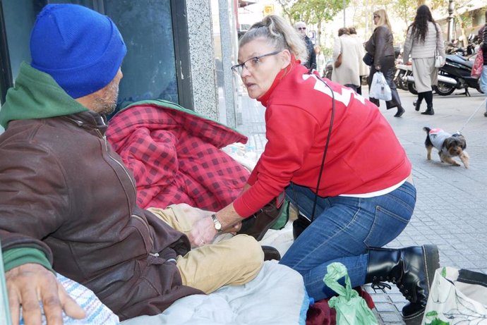 Archivo - Una voluntaria de Cruz Roja junto a una persona sin hogar, en una imagen de archivo.