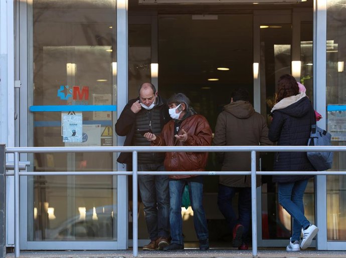 Dos personas con una mascarilla en la cara conversan a su salida de un centro de salud, a 8 de enero de 2024