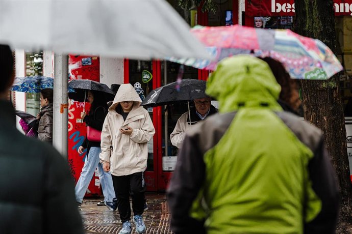 Archivo - NVarias personas se protegen de la lluvia con paraguas, en una foto de archivo
