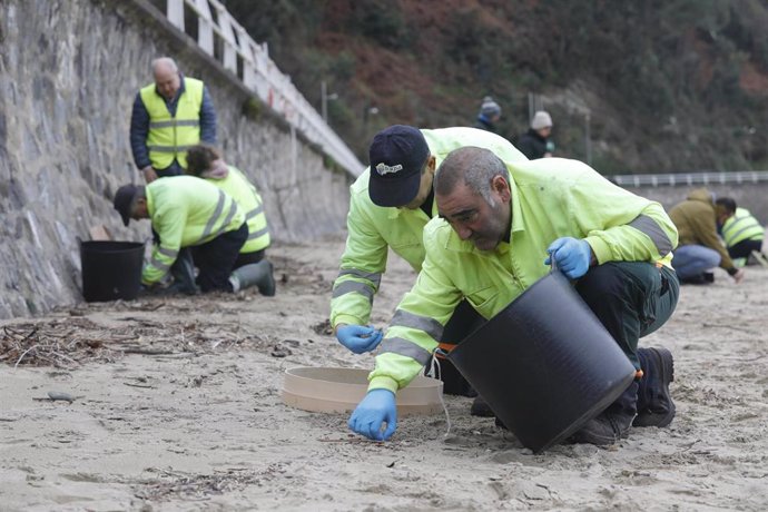 Operarios de TRAGSA recogen pellets de plástico, en la playa de Aguilar, a 9 de enero de 2024, en Muros de Nalón, Asturias (España). El Principado de Asturias ha activado el nivel dos de emergencia por el vertido de pellets de plástico en las playas de la