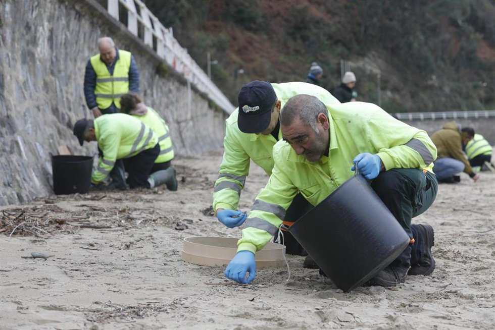 Operarios de TRAGSA recogen pellets de plástico, en la playa de Aguilar, a 9 de enero de 2024, en Muros de Nalón, Asturias (España). El Principado de Asturias ha activado el nivel dos de emergencia por el vertido de pellets de plástico en las playas de 