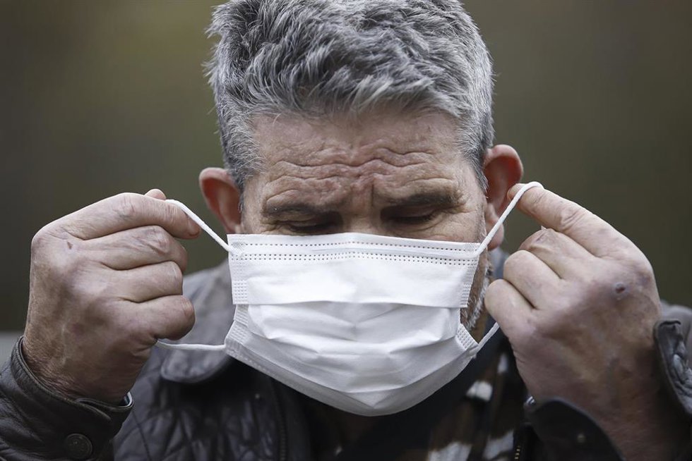 Un hombre se pone la mascarilla.