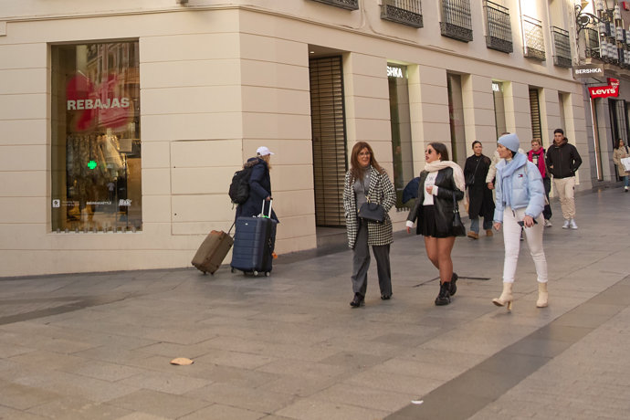 Varias personas caminan delante de un escaparate 