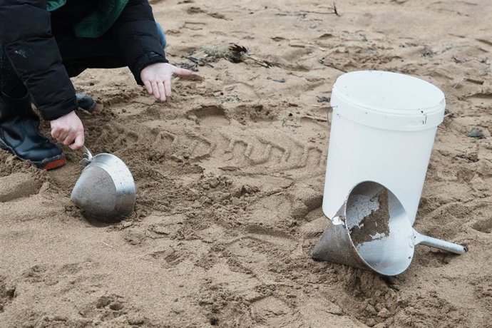 Archivo - Un voluntario recoge pellets en la playa de La Arena