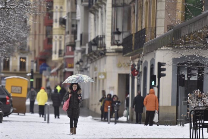 Una mujer sujeta un paraguas mientras camina por una calle de nieve, a 10 de enero de 2024, en Jaca, Huesca, Aragón (España). 