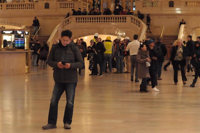 January 9, 2024, New York, United States: A person uses a cell phone while pedestrians walk through the main concourse of Grand Central Terminal in midtown Manhattan, New York City.