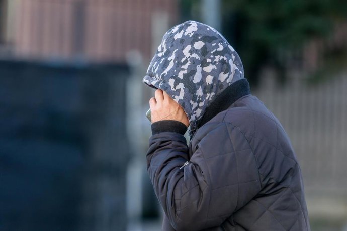 Archivo - Un hombre pasea abrigado con capucha.