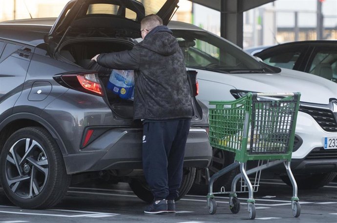Archivo - Un hombre mete la compra en el maletero de su vehículo, al salir de un supermercado.