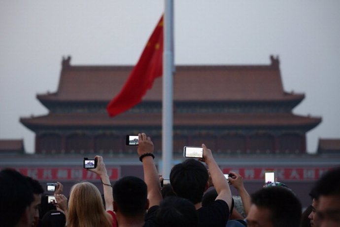 Archivo - Chinese tourists watch the customary ceremony of lowering flag at Tiananmen Square on June 3, 2013 in Beijing, China.