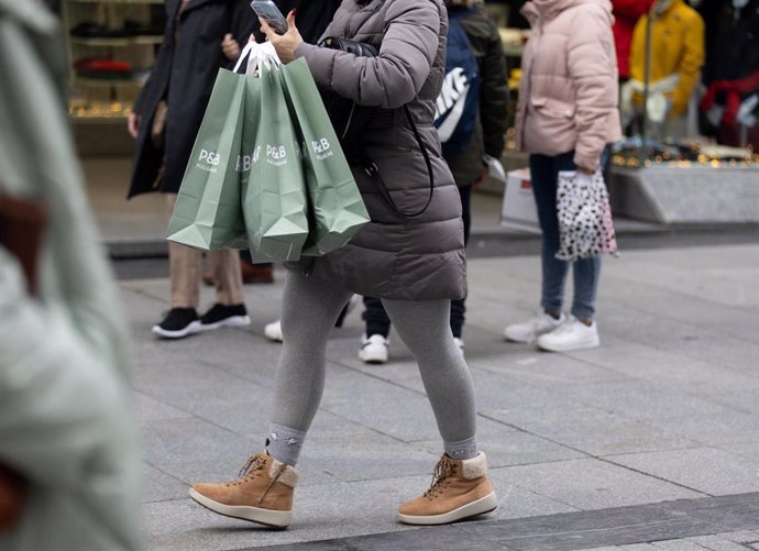 Archivo - Una persona sujeta varias bolsas con compras de Navidad.