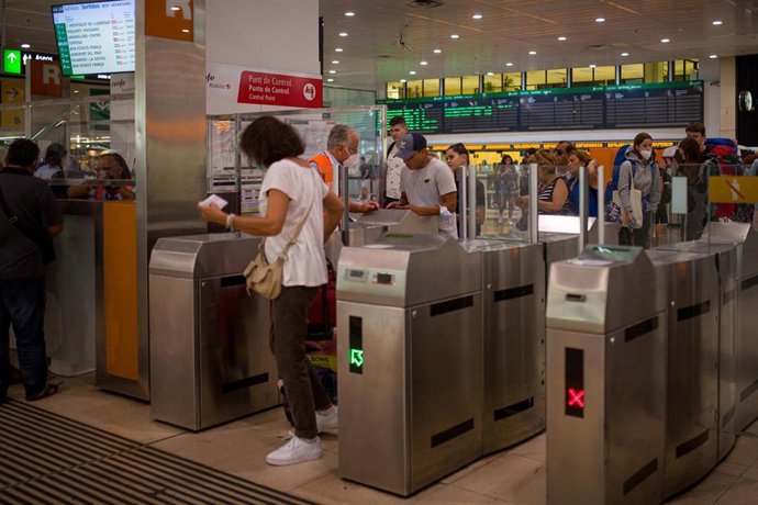 Archivo - Viajeros cruzan los tornos de la estación de Sants, a 9 de septiembre de 2022, en Barcelona